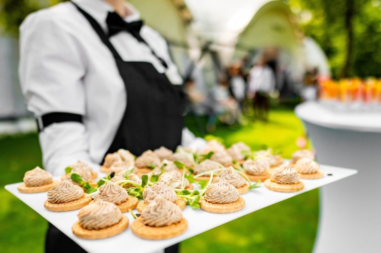 Event hire includes weddings, parties and festivals A waiter holding a platter of canapés in a garden setting.