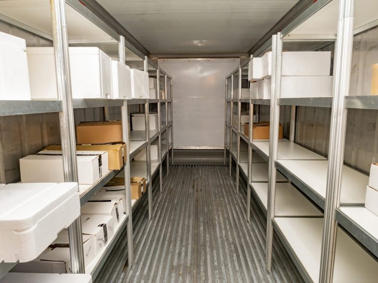 We can repair your equioment and help you keep stock cool with wrap around services Interior of a chilled storage unit with shelves filled with polystyrene fish boxes and some cardboard boxes.